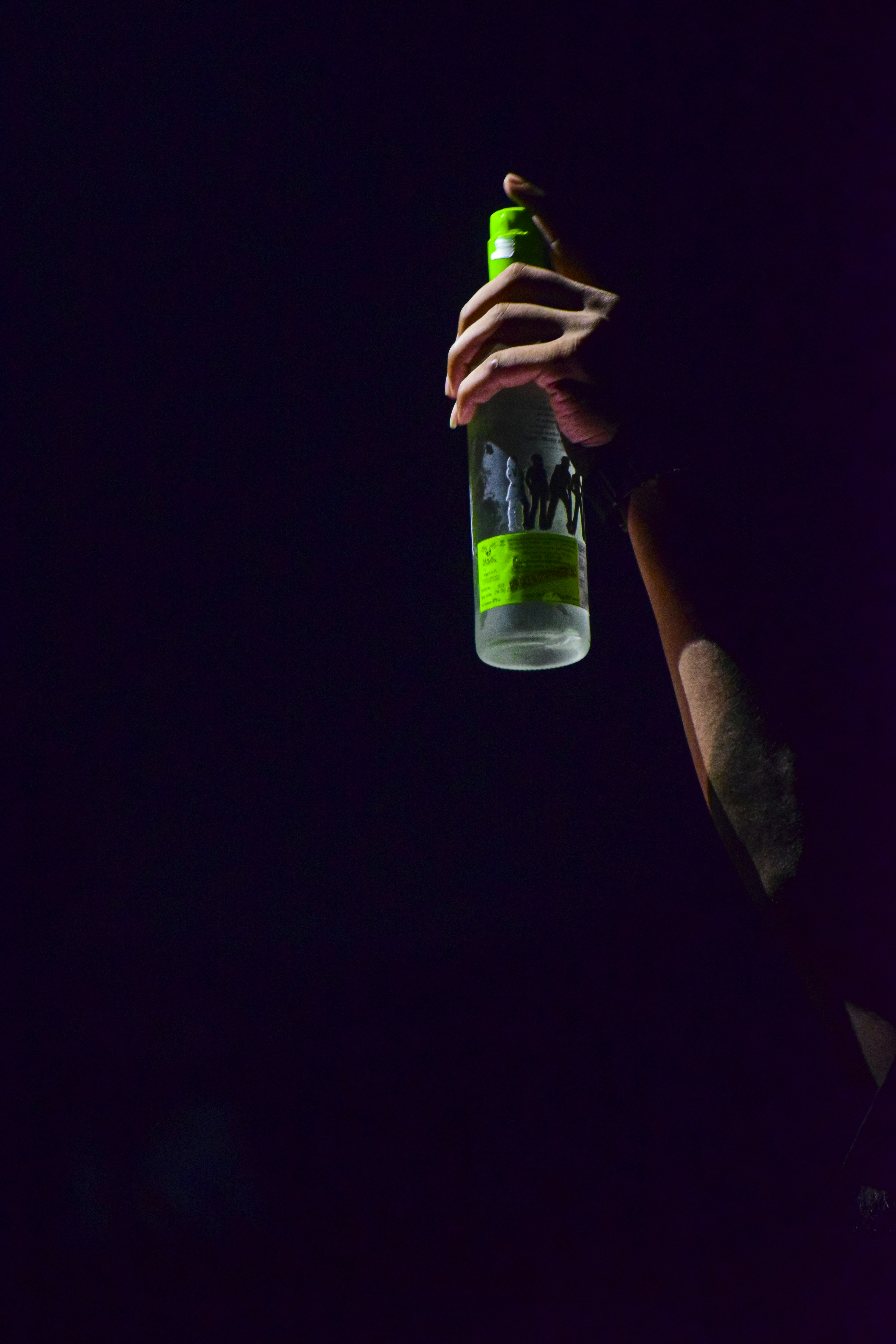 a person holding a bottle in the dark