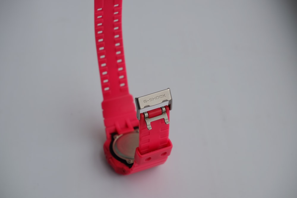 a pink watch with a metal clasp on a white surface