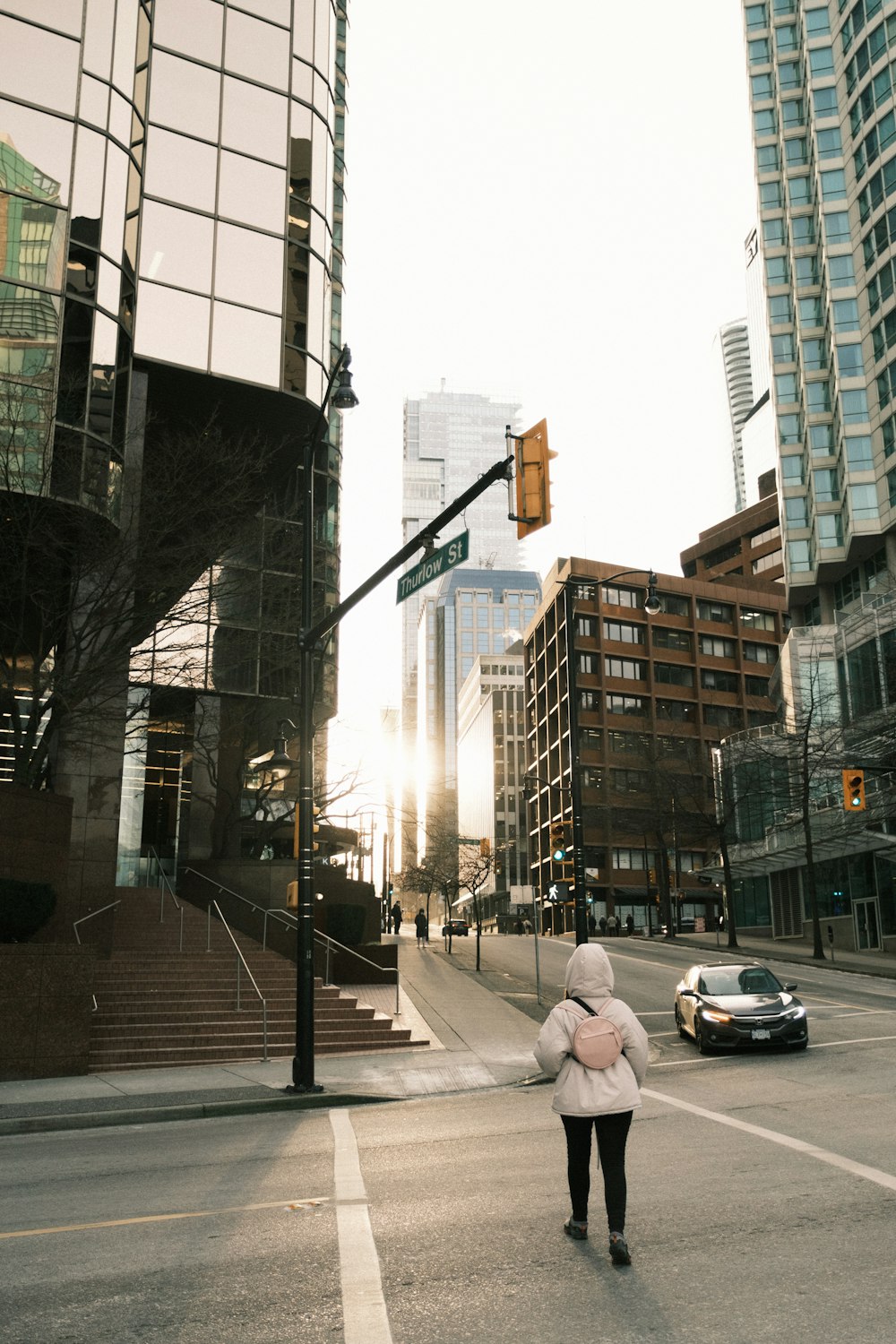 a woman walking across a street next to tall buildings