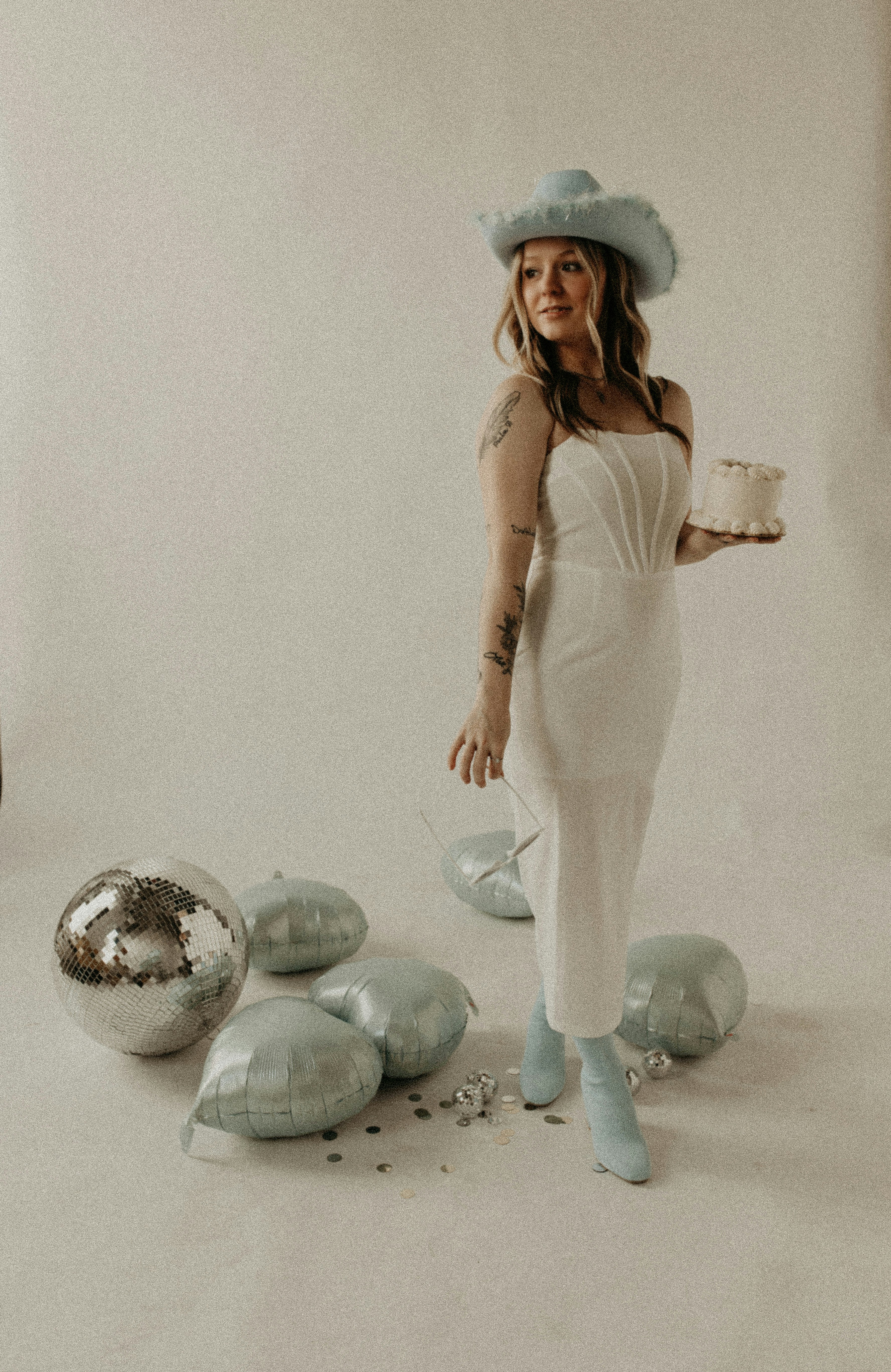 白いドレスと帽子をかぶった女性がケーキを手に