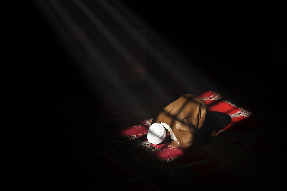 une personne allongée sur un tapis dans l’obscurité