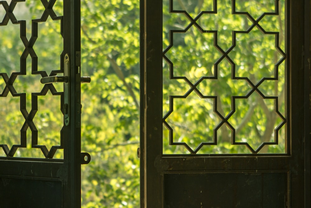 a close up of a metal door with a tree in the background