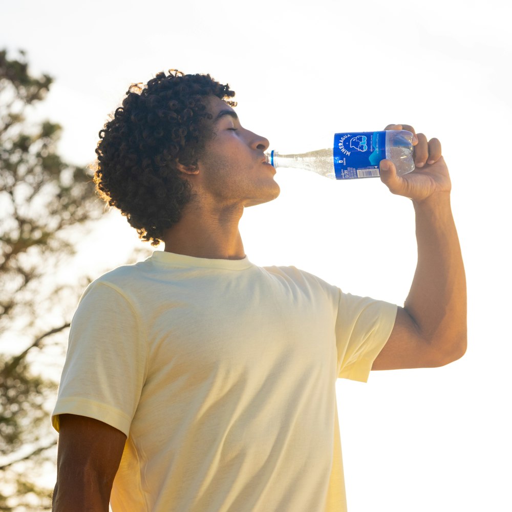 a young man drinking water from a bottle