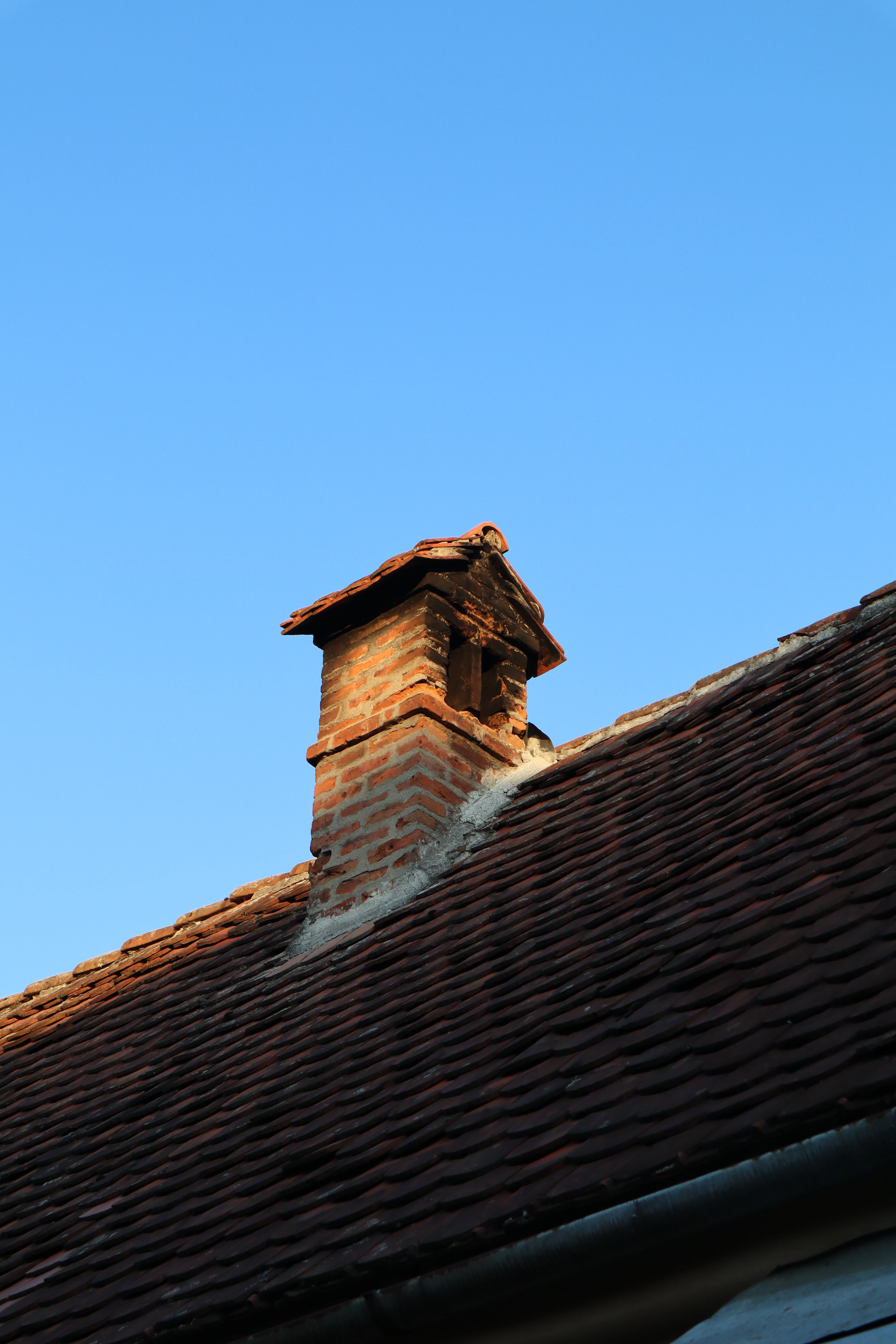 Representative image of brick chimney on rooftop for draft troubleshooting; not a Fireplace Gallery installation