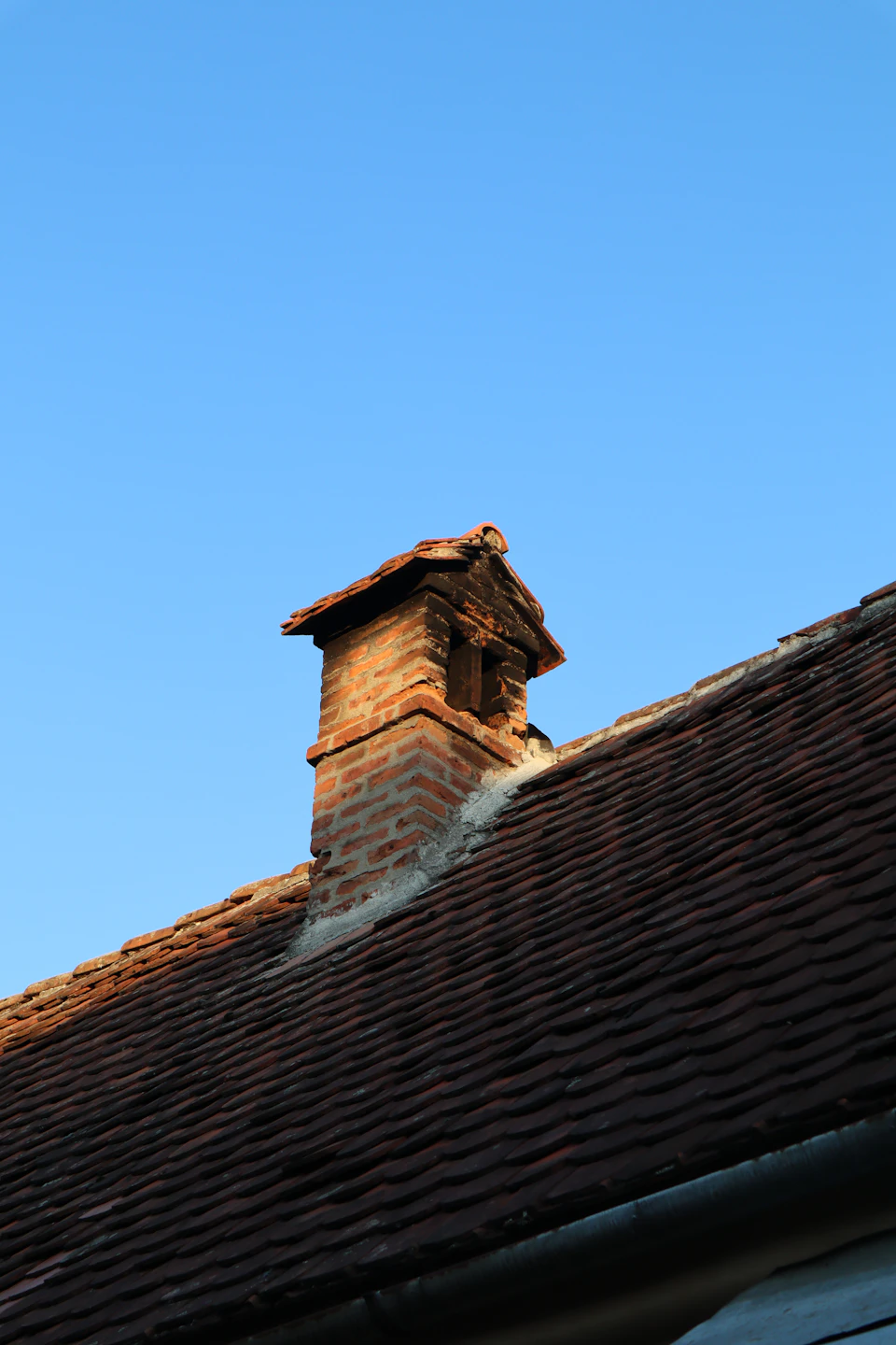 Representative image of brick chimney on rooftop for draft troubleshooting; not a Fireplace Gallery installation