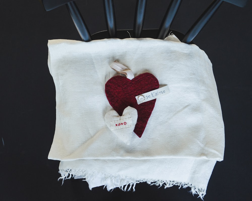 Un corazón rojo está sobre una toalla blanca