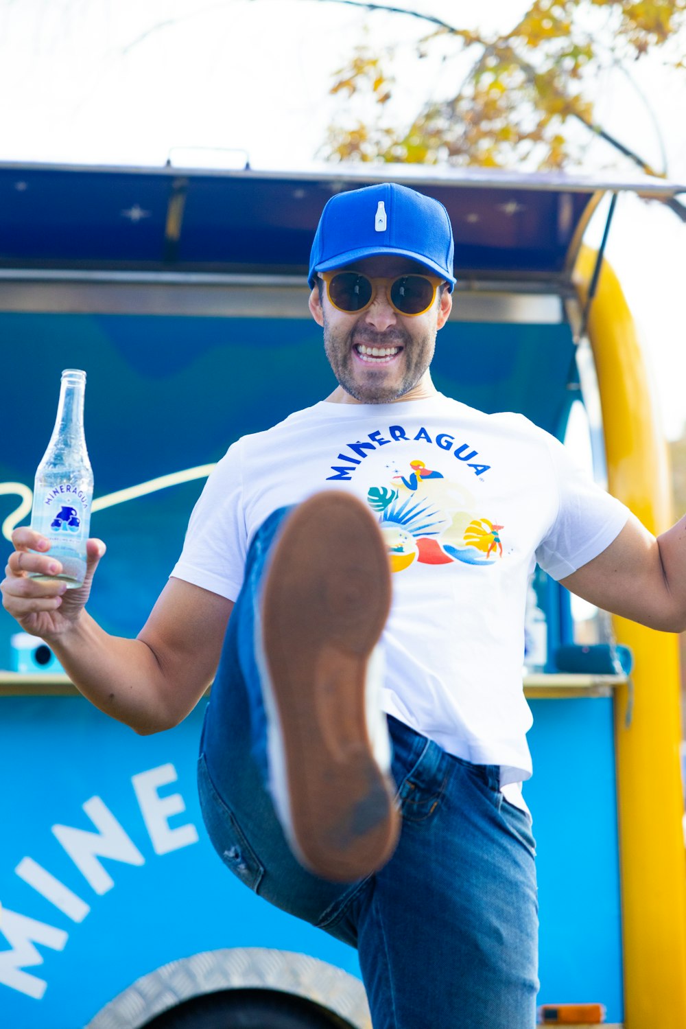 a man in a blue hat and sunglasses holding a bottle of water