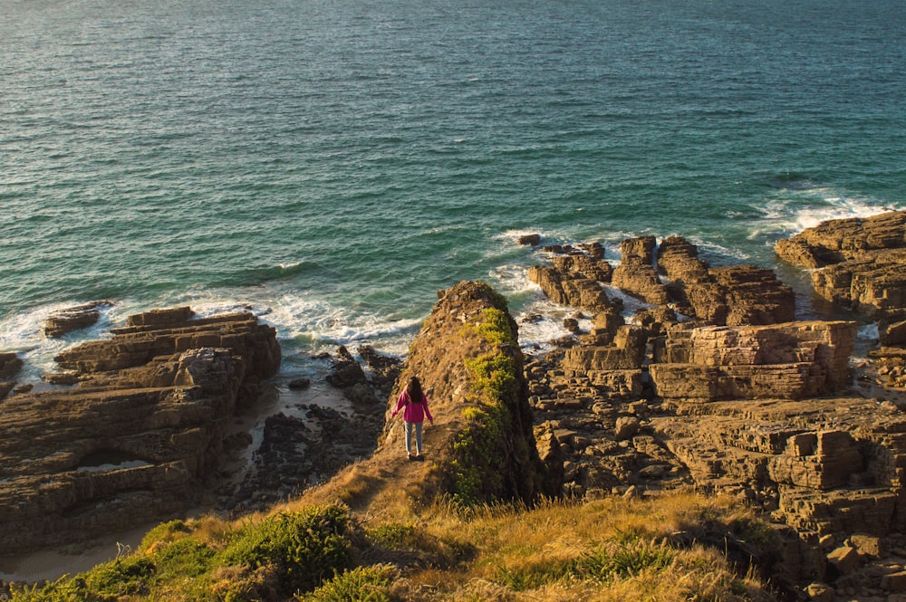 a person standing on top of a cliff near the ocean