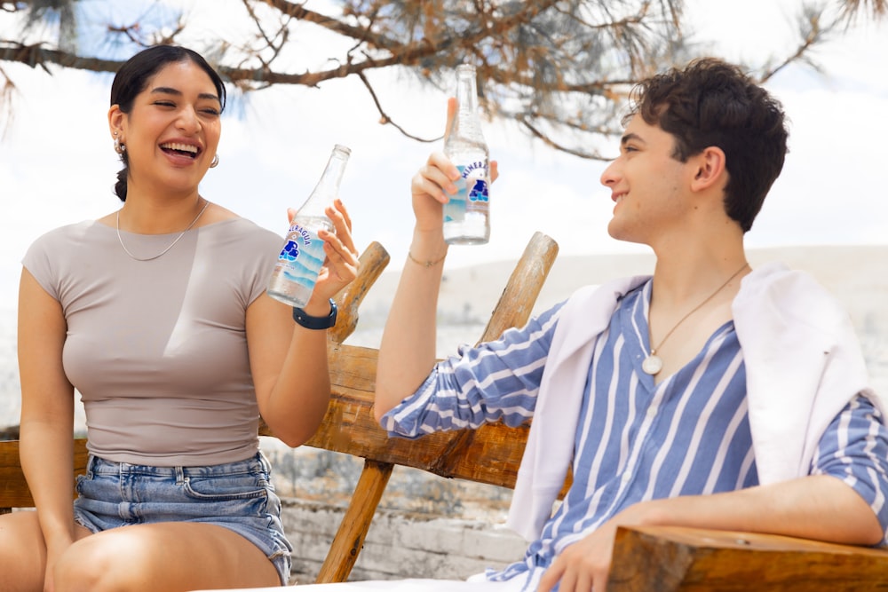 un hombre y una mujer sentados en un banco bebiendo agua