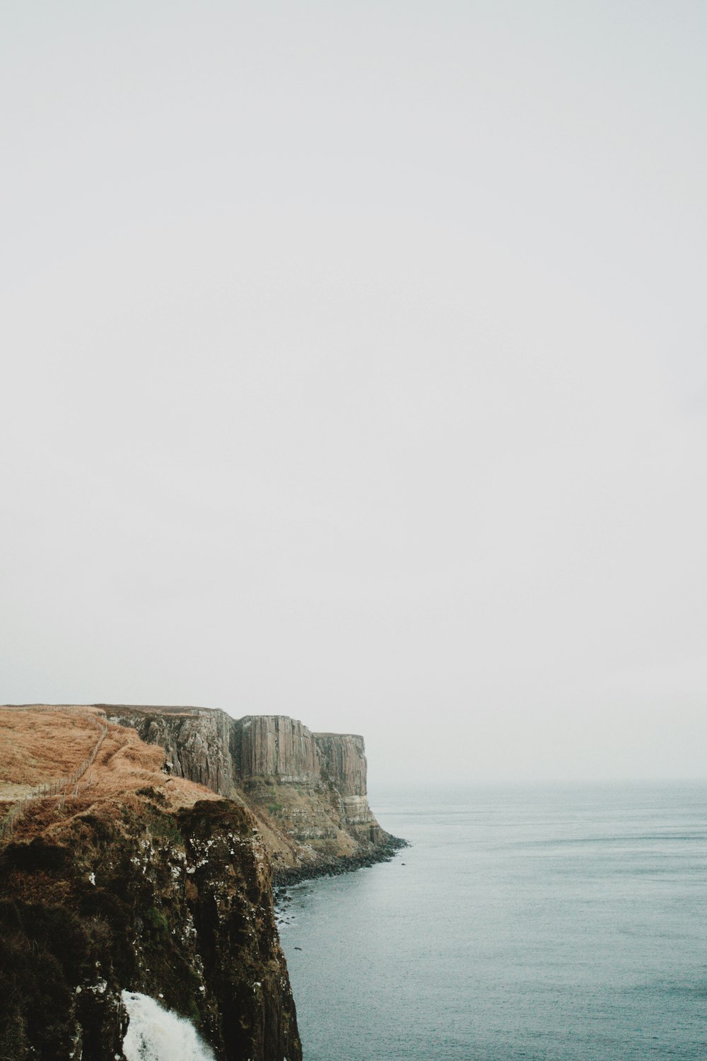 a person standing on top of a cliff next to the ocean