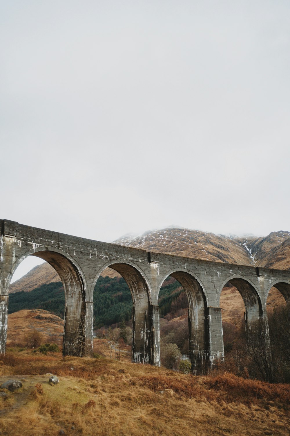 an old stone bridge with arches in the middle of a field