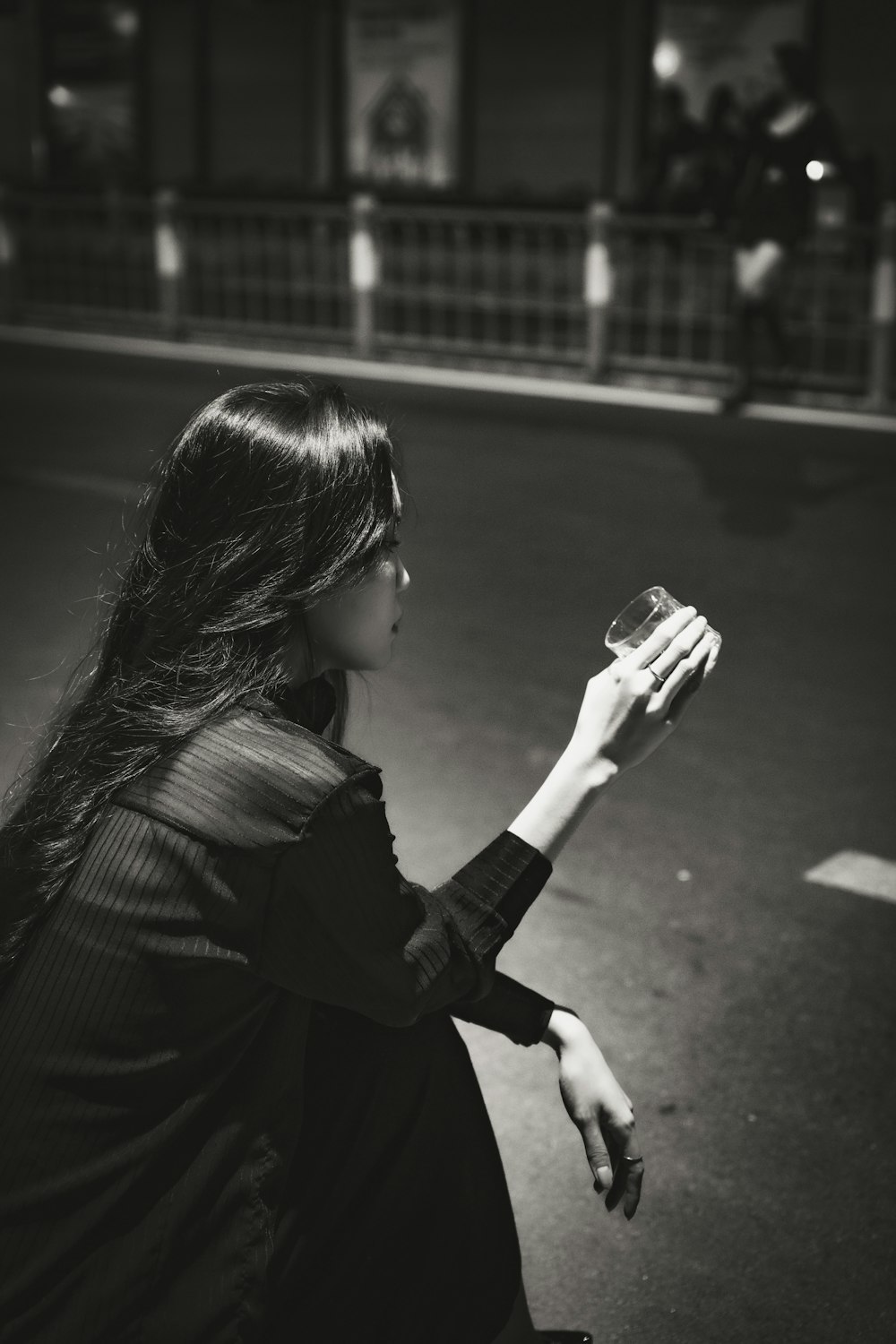 a black and white photo of a woman sitting on the street
