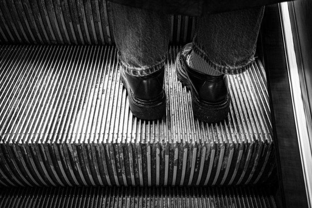 black and white photograph of a person's feet on an escalator