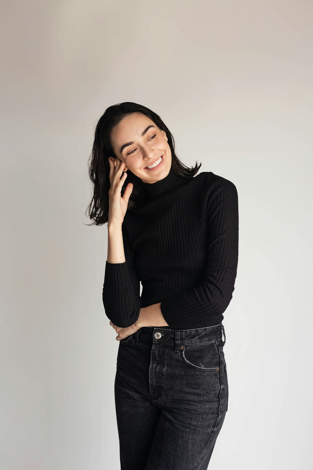 a woman in a black sweater and jeans talking on a cell phone