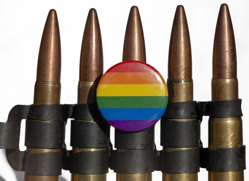 um botão colorido do arco-íris sentado em cima de um monte de cabeças de bala