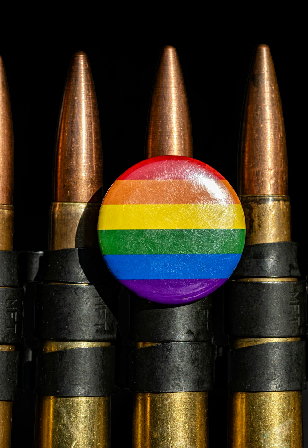 um botão colorido do arco-íris sentado em cima de um monte de projéteis de bala