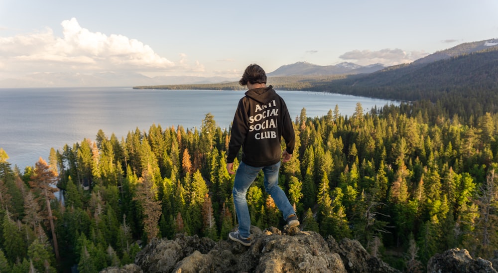 a man standing on top of a cliff overlooking a lake