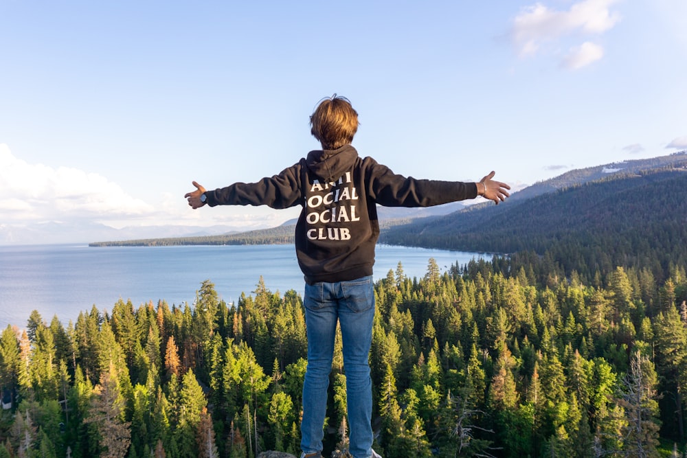 a man standing on top of a cliff overlooking a lake