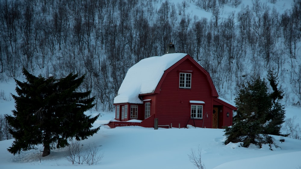 una casa roja en medio de un bosque nevado