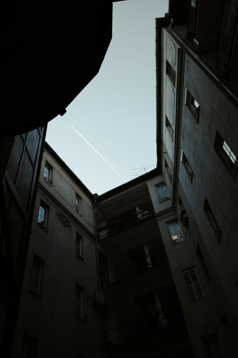 an upward view of a building with a plane in the sky