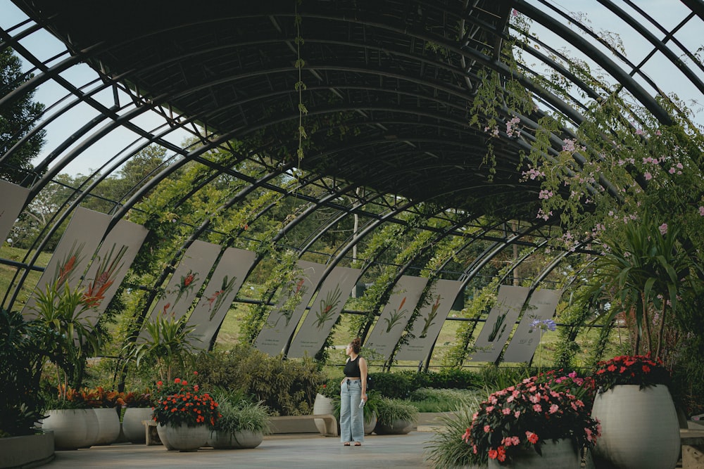 a woman is walking through a garden area