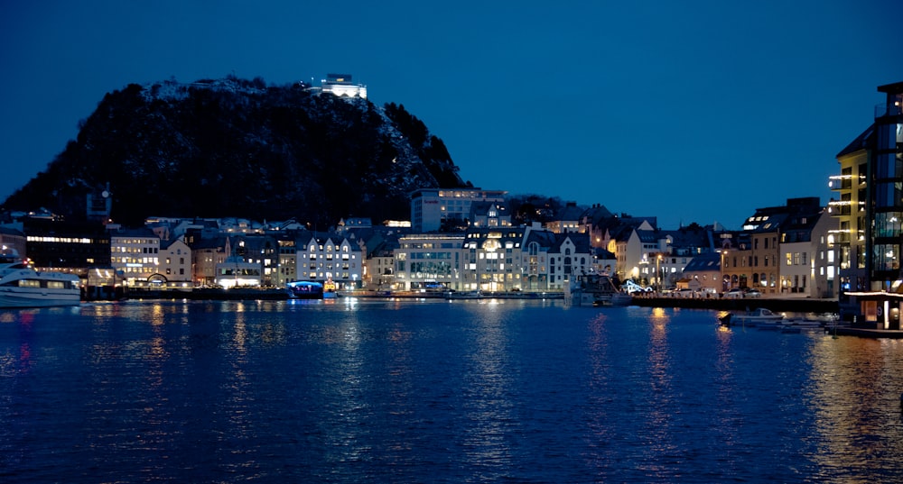 a body of water with buildings on a hill in the background