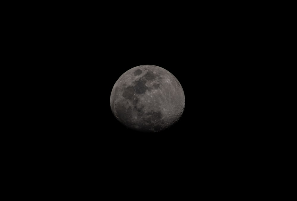 a full moon is seen in the dark sky