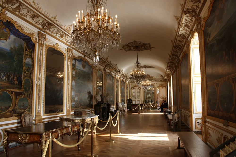 a hallway with a chandelier and paintings on the walls