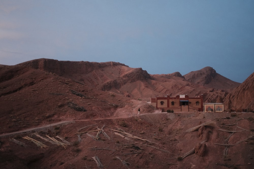 uma casa no meio de um deserto com montanhas ao fundo