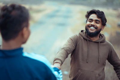 a man with a beard smiles as another man holds his hand out