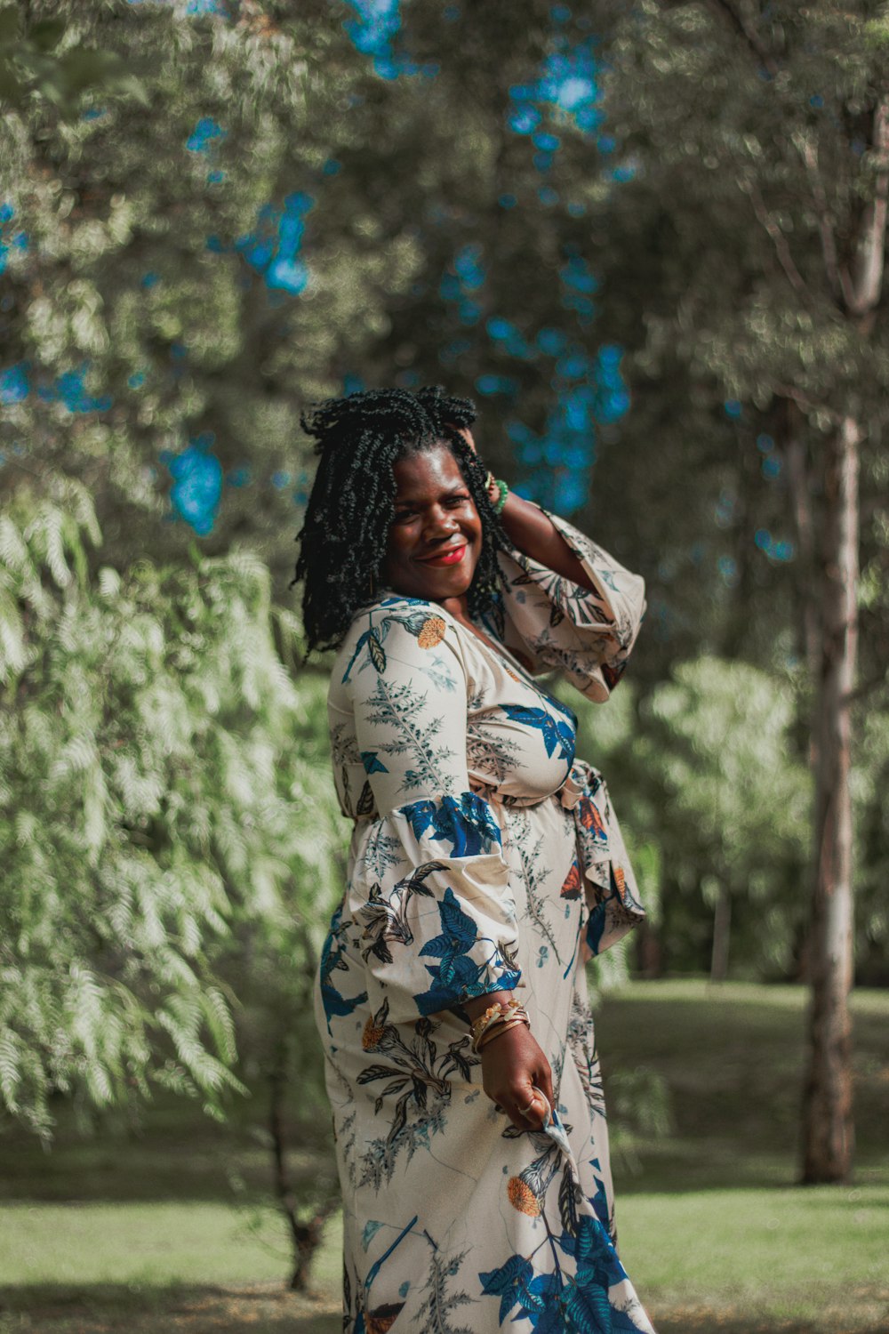 une femme en robe à fleurs debout dans un parc