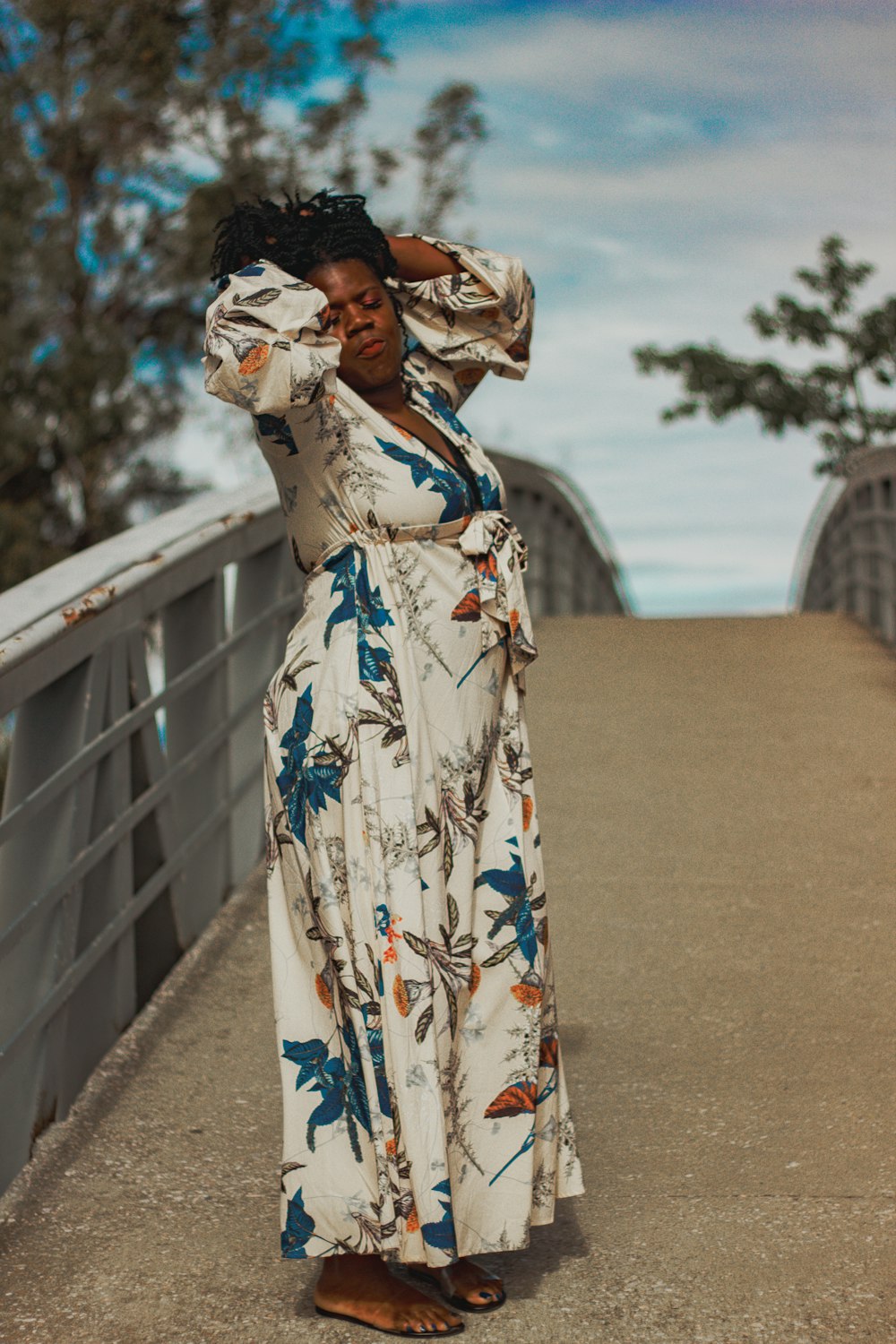 a woman standing on a bridge with her arms behind her head