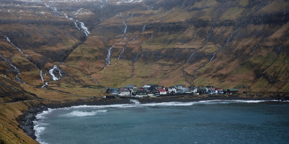 a small village on the side of a mountain next to a body of water