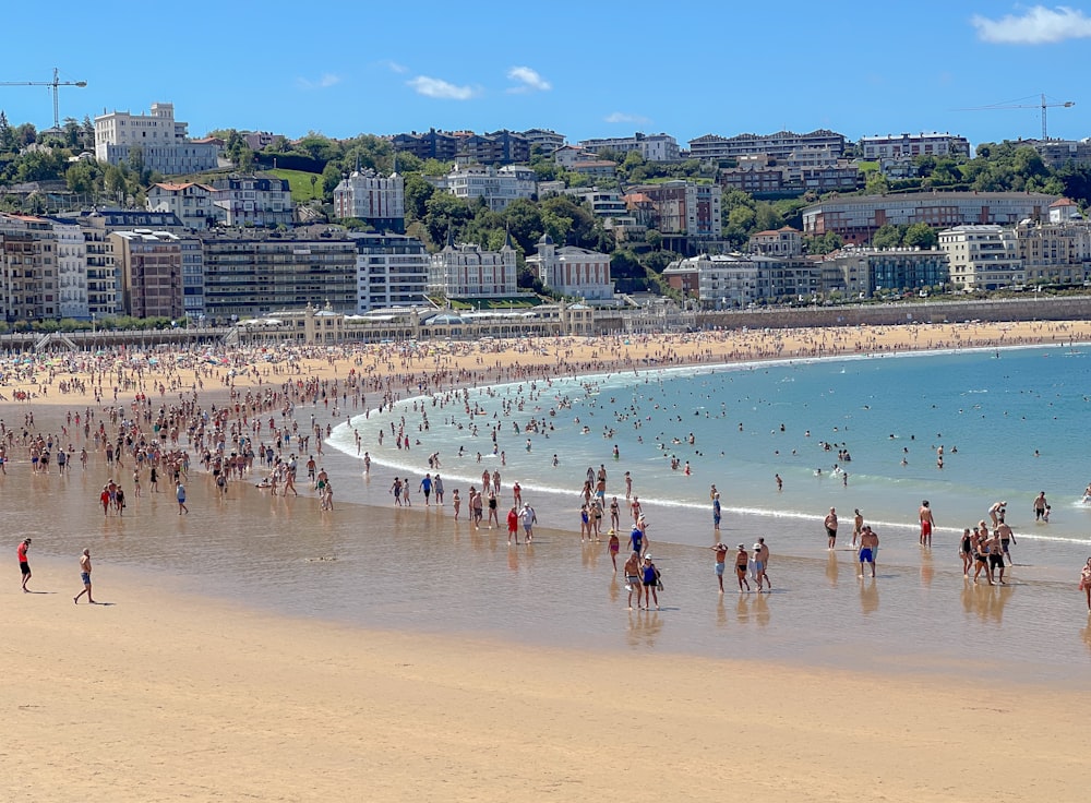 un grande gruppo di persone in piedi su una spiaggia vicino all'oceano