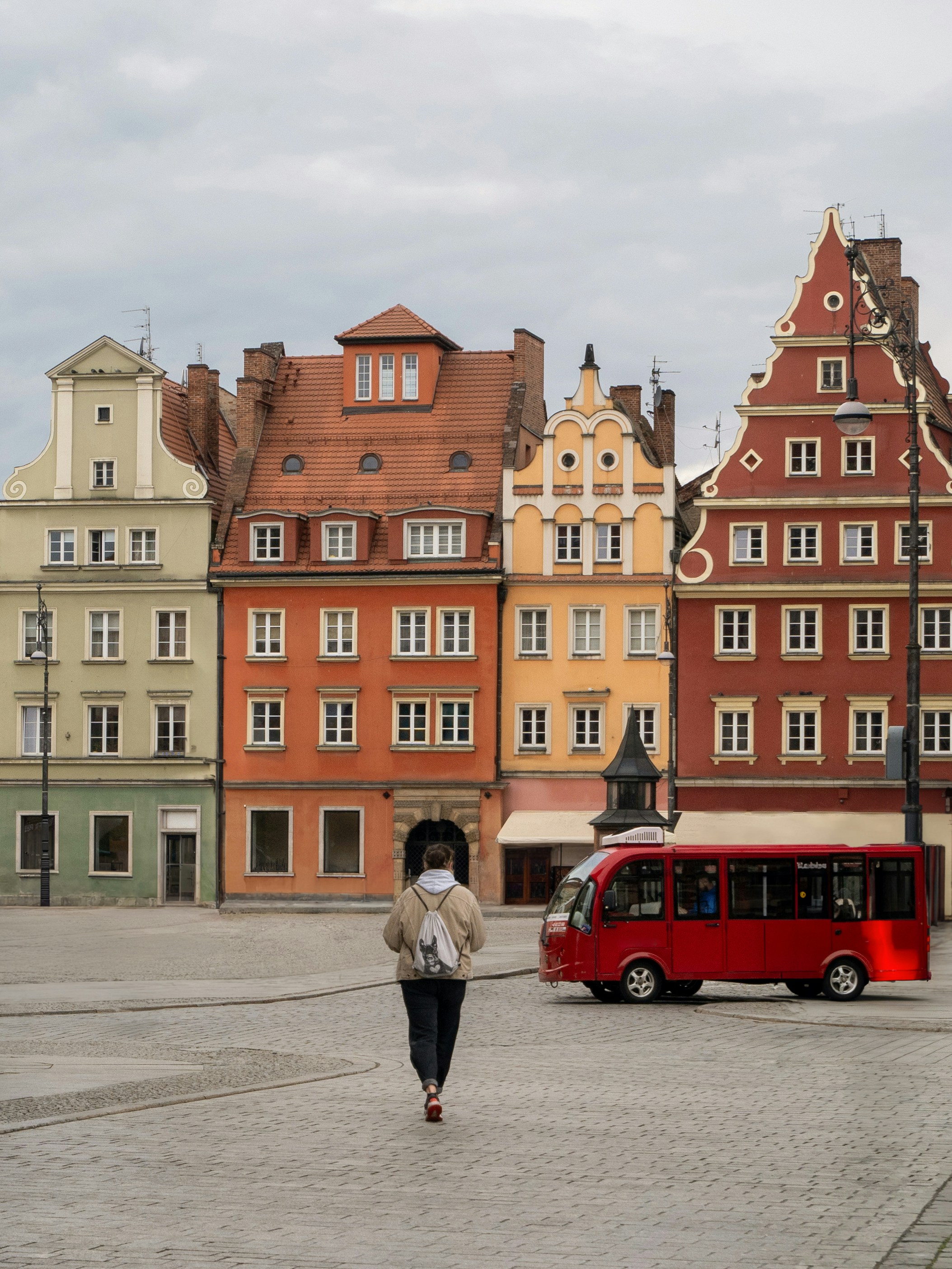 a woman walking in front of a red bus