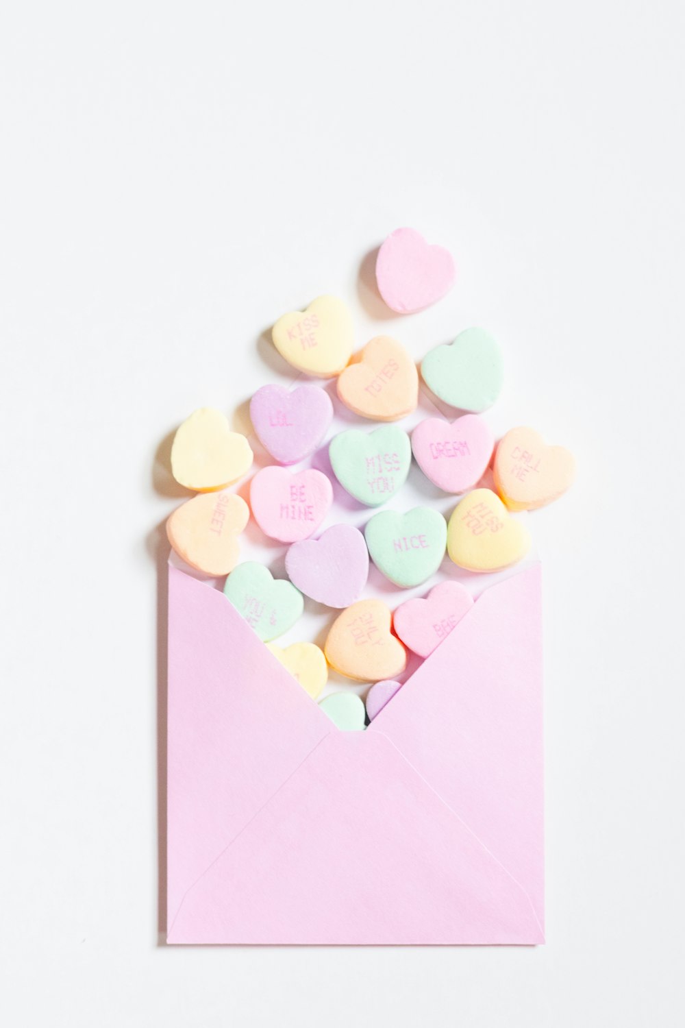 a pink envelope filled with conversation hearts