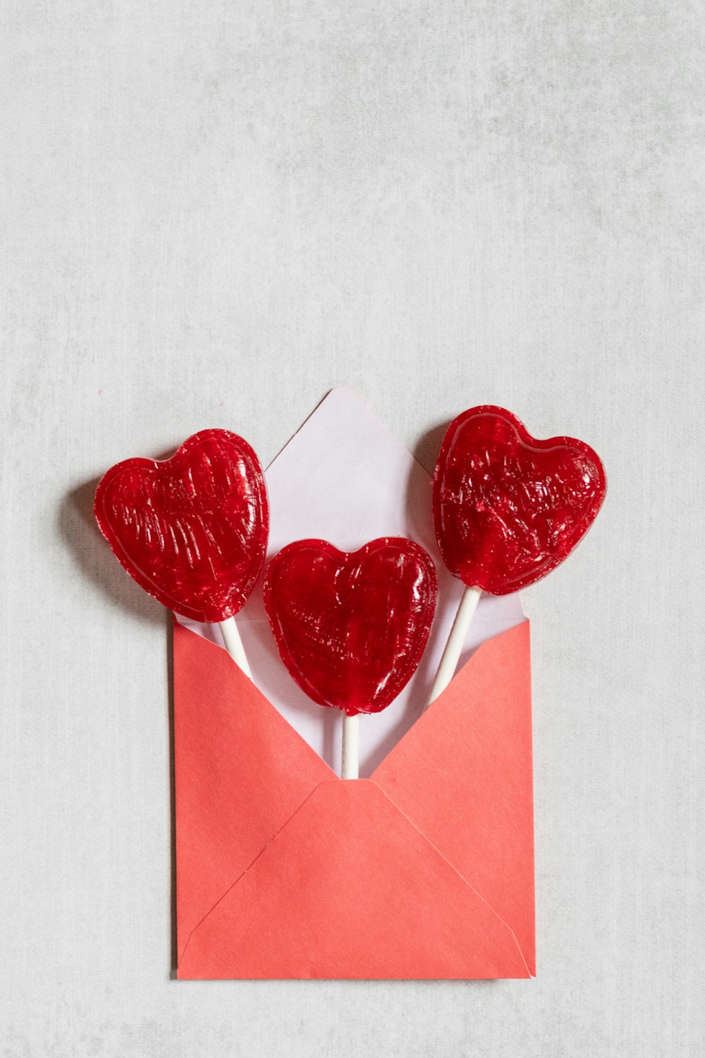 two heart shaped lollipops sticking out of an envelope