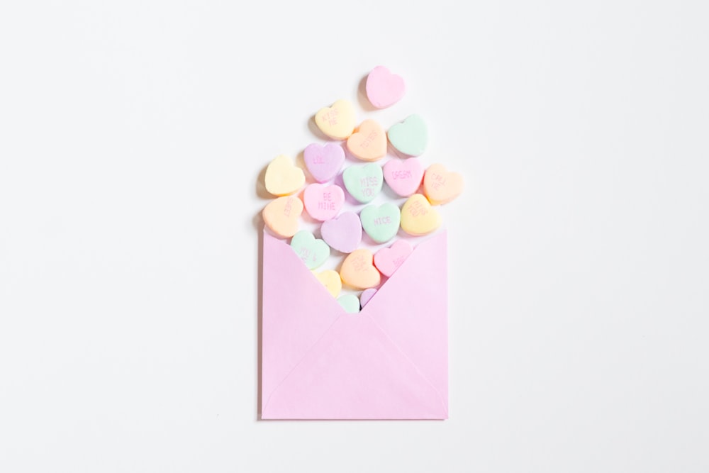 a pink envelope filled with conversation hearts