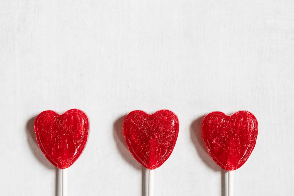 three lollipops shaped like hearts on a stick
