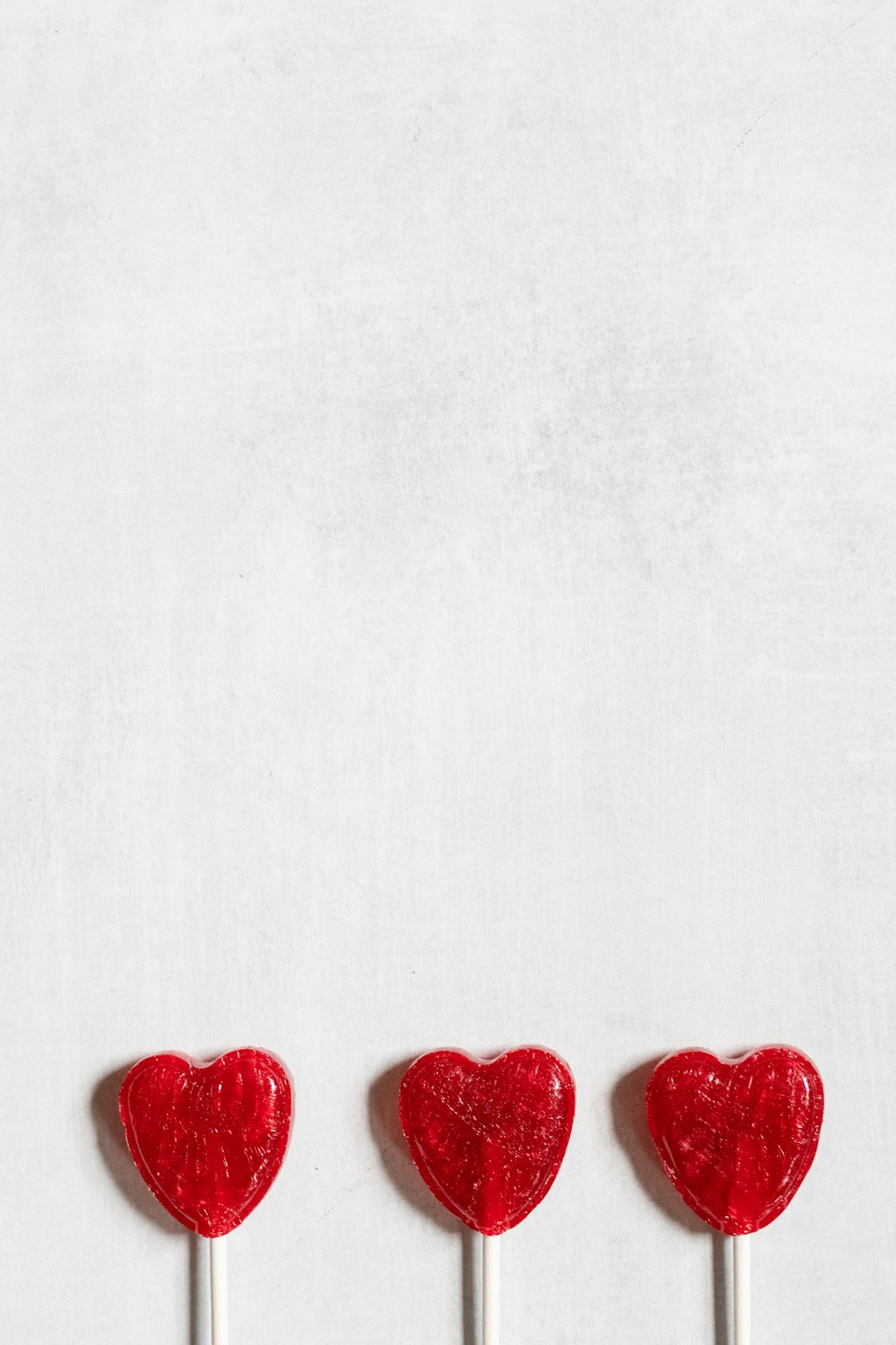 three lollipops shaped like hearts on a stick