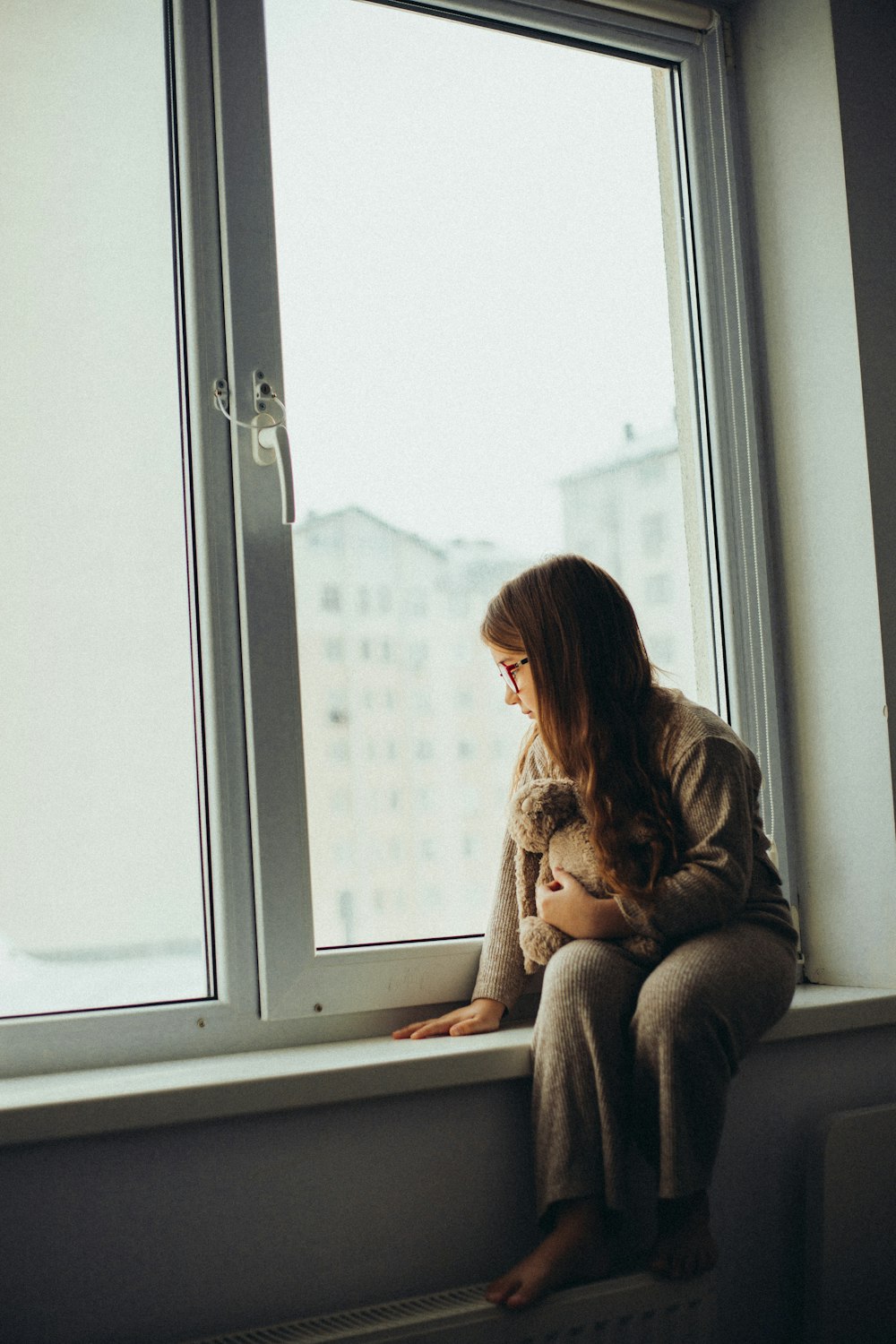 a woman sitting on a window sill holding a cat
