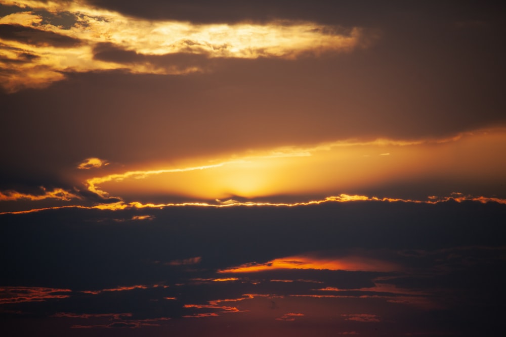 a plane flying in the sky at sunset