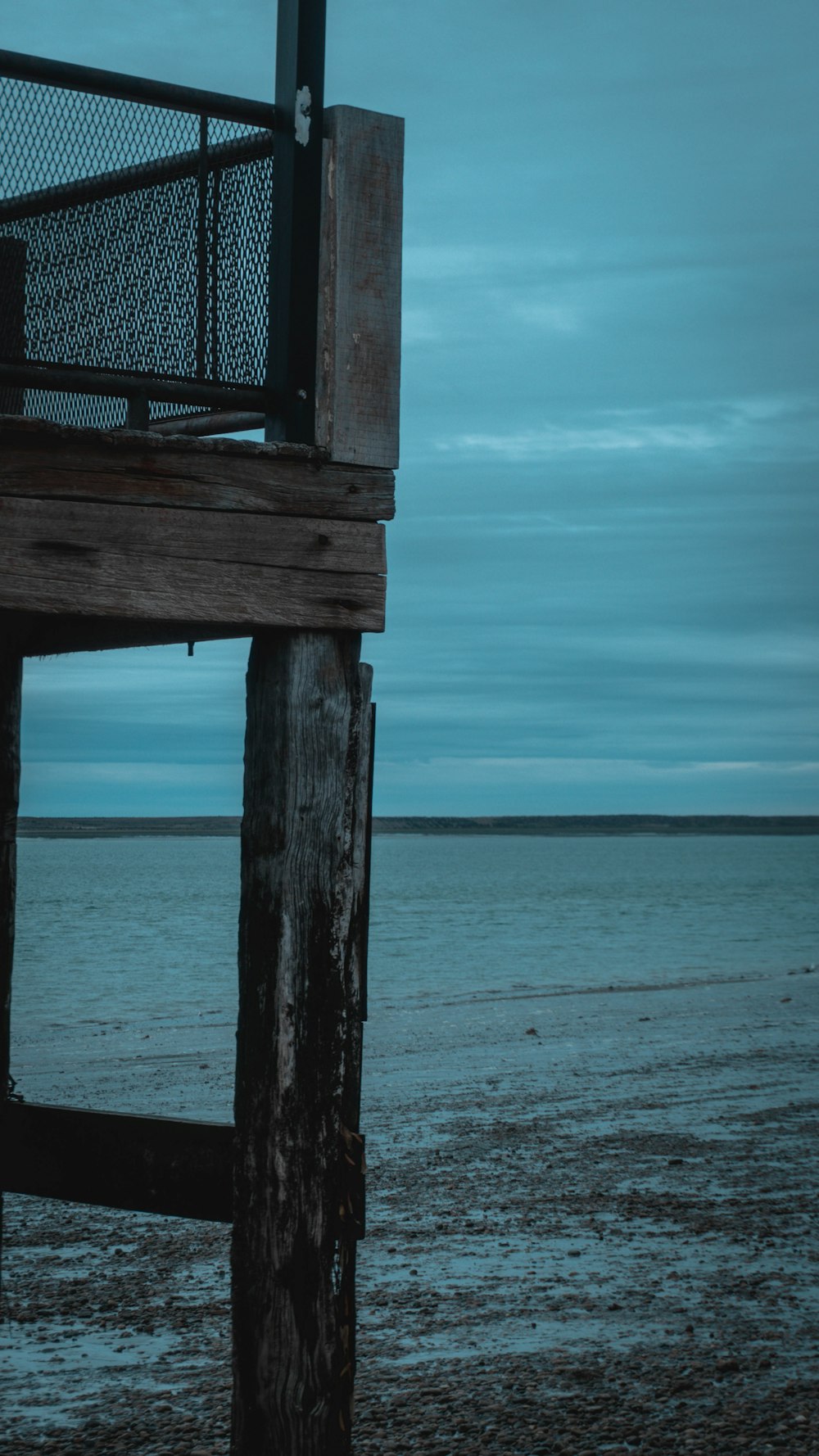 a wooden structure sitting on top of a beach next to the ocean