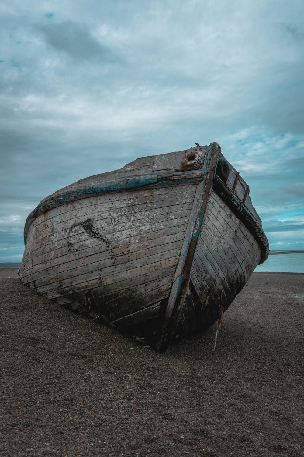 an old boat sitting on top of a sandy beach