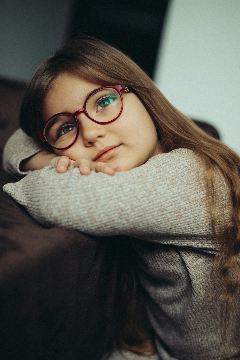 a young girl wearing glasses sitting on a couch