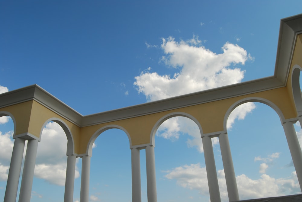 a row of white pillars under a cloudy blue sky
