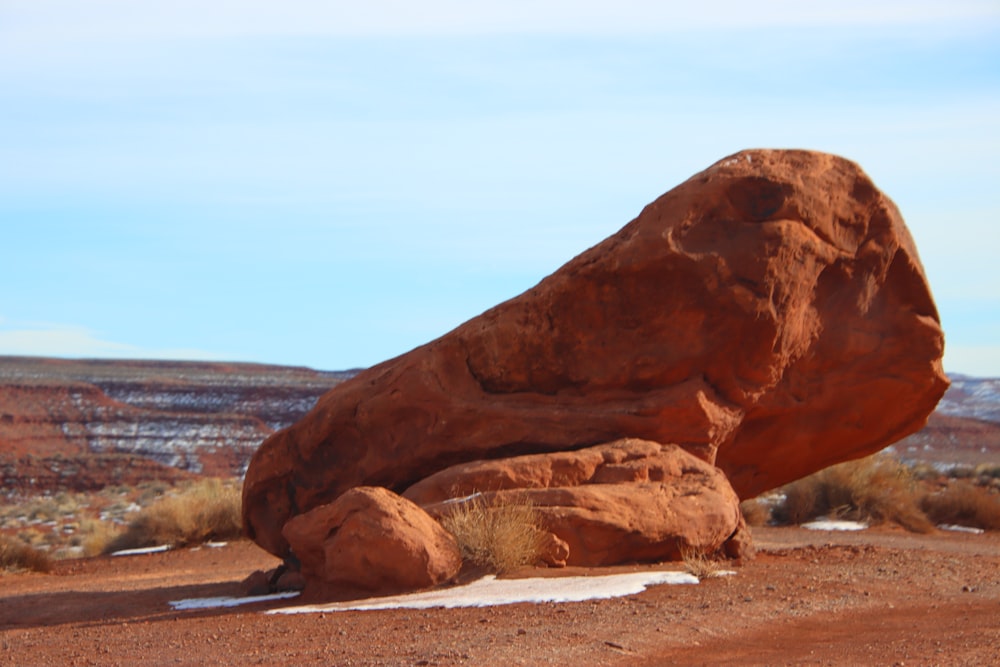 a large rock sitting in the middle of a desert