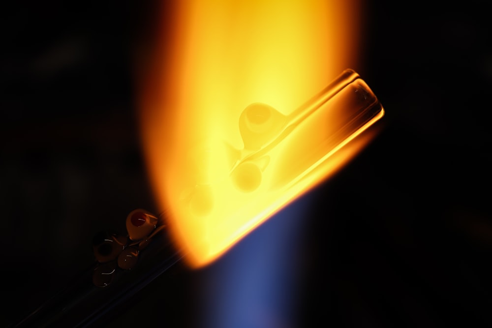 a close up of a piece of metal with a flame in the background
