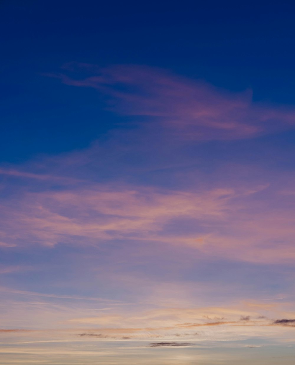 a plane flying in the sky at sunset