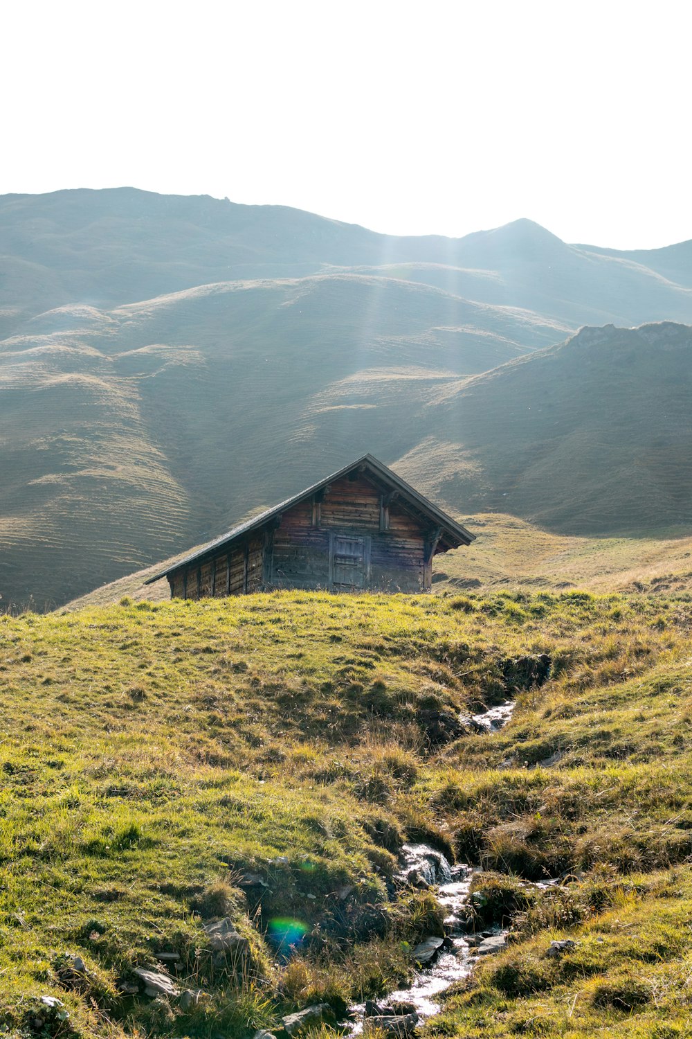 a small cabin sitting on top of a lush green hillside